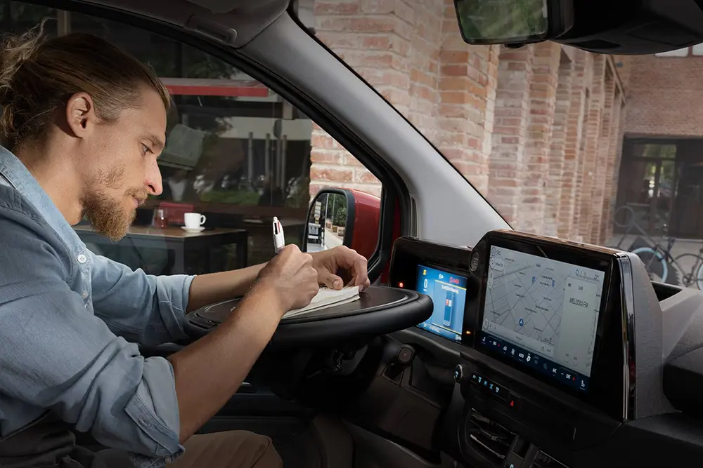 Ford Transit Custom - Mann sitzt im Transit und notiert sich etwas - Ford im Autocenter Mothor in Stendal, Gardelegen und Brandenburg kaufen, leasen oder finanzieren.