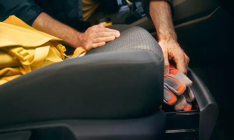 Der Volkswagen Caddy Cargo - Mann legt Arbeitshandschuhe in ein Fach - Jetzt deinen Volkswagen bei deinem Volkswagen Autohaus Mothor in Brandenburg leasen oder finanzieren oder kaufen