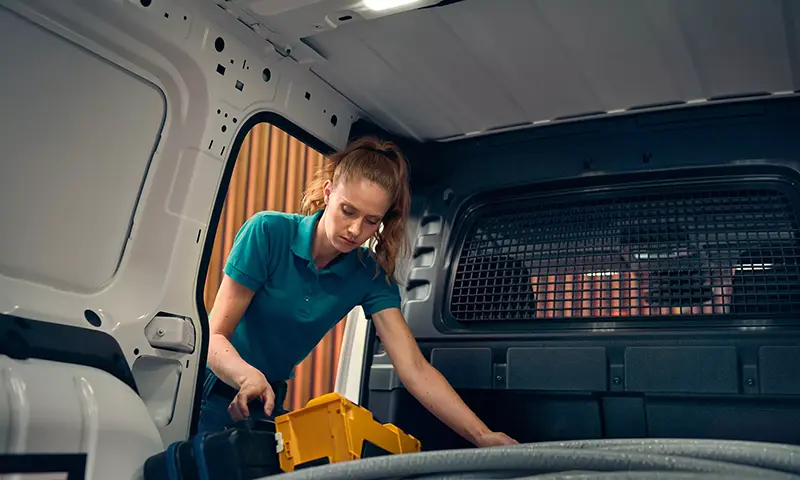 Der Volkswagen Caddy Cargo - Handwerkerin legt etwas in den Caddy Cargo - Jetzt deinen Volkswagen bei deinem Volkswagen Autohaus Mothor in Brandenburg leasen oder finanzieren oder kaufen