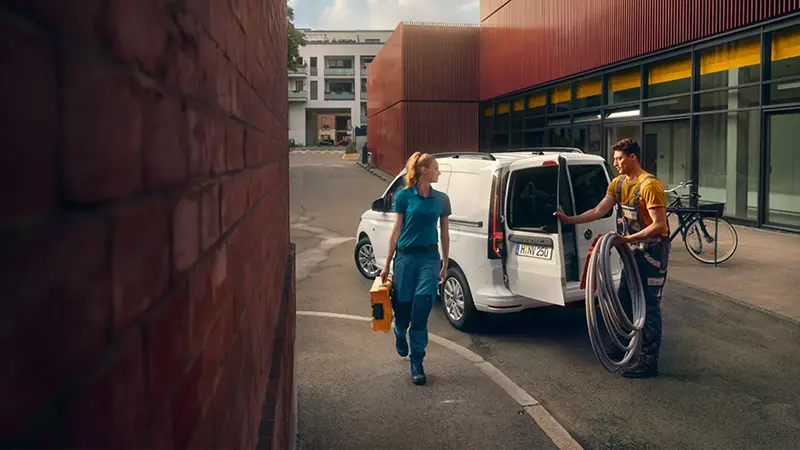 Der Volkswagen Caddy Cargo - zwei Handwerker*innen beim Entladen von Arbeitsmaterial - Jetzt deinen Volkswagen bei deinem Volkswagen Autohaus Mothor in Brandenburg leasen oder finanzieren oder kaufen